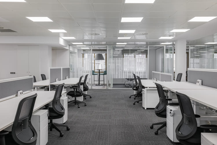 Modern commercial office space with large windows, open work areas, and professional furnishings.