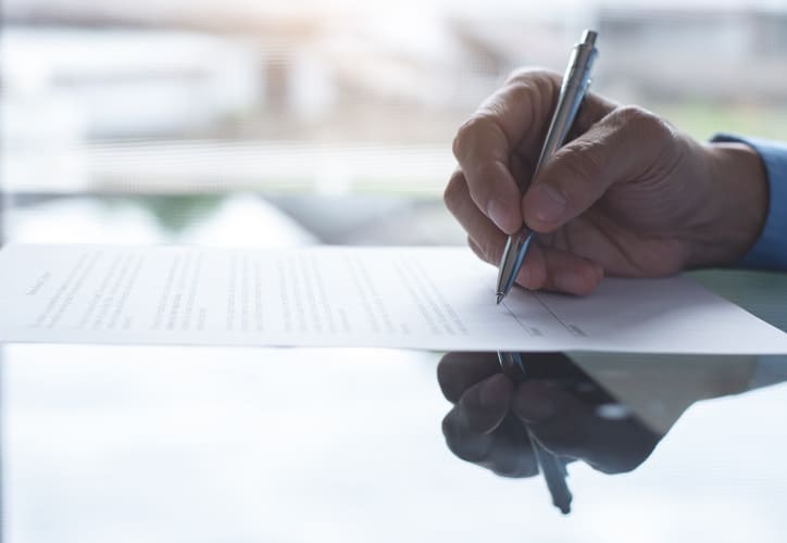 Person signing a lease agreement with a pen on a document